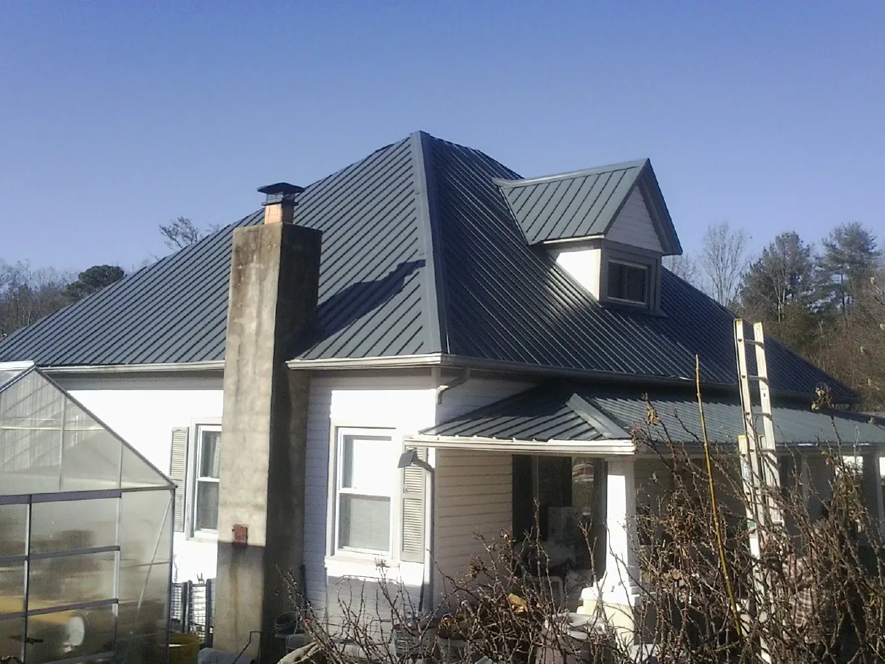Dark blue standing seam metal roof on a white farmhouse with dormer — Slate & Tile Roof Repair by Roofing Brothers in Palouse