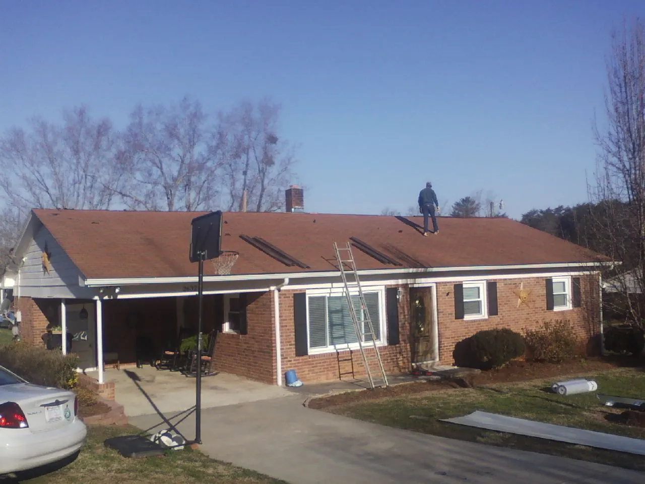 Roofer stripping a shingle roof on a brick ranch before metal panels in Palouse