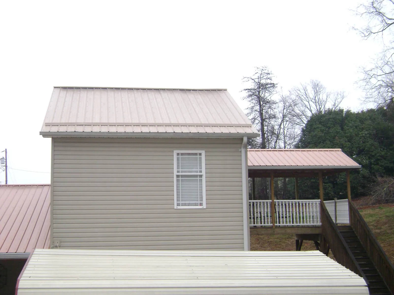 Tan metal roofs on a two story addition and attached porch, from a Roof Replacement job in Palouse