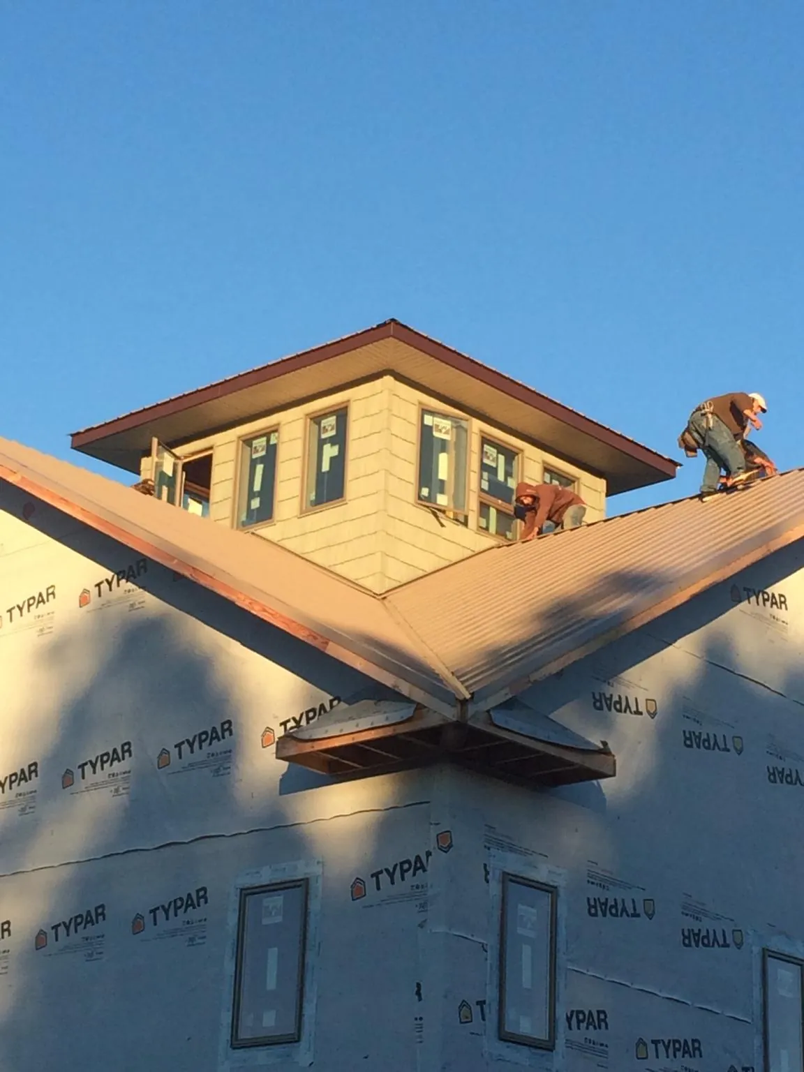 Roofers working around a rooftop cupola on a new metal roof at sunset — Roof Waterproofing in Palouse by Roofing Brothers